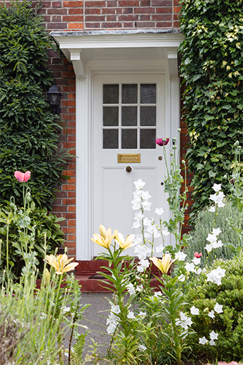 Elegant entrance with climbing vines and white door - Ground-Up Spec Homes